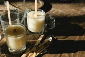 Velas hechas a mano en un taller artesanal con luz natural y herramientas de madera.